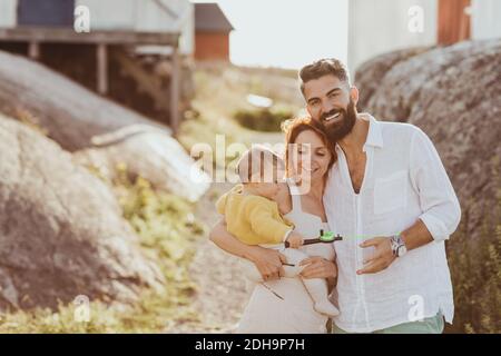 Portrait von lächelnden Vater steht bei Frau trägt Baby Mädchen Über dem Archipel Stockfoto