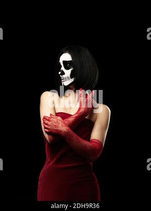 Frau in einem roten Samtkleid gekleidet, lange Netzhandschuhe. Halloween Skelett Make-Up Stockfoto