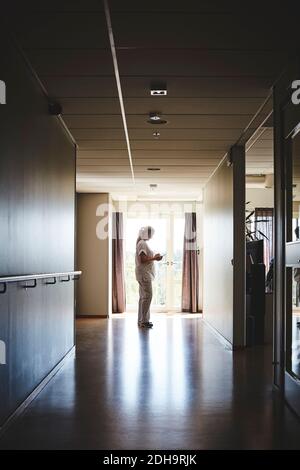 Seitenansicht der Krankenschwester in voller Länge mit digitalem Tablet Im Krankenhausflur Stockfoto