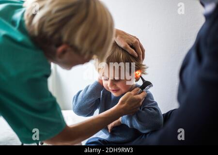 Ärztin, die im Krankenhaus das Ohr des Jungen mit Otoskop untersucht Stockfoto