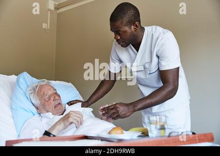 Krankenschwester gibt Hustensirup an älteren Mann im Krankenhaus Station Stockfoto