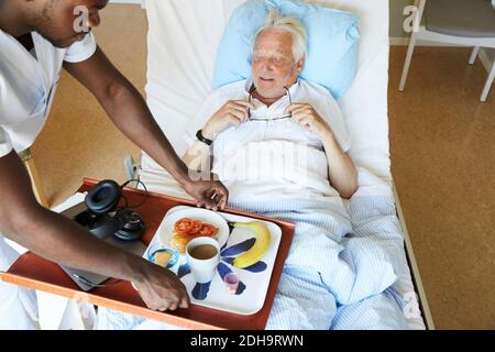 Aus der Sicht des Krankenpflegers, der dem Senioren das Frühstück serviert Mann auf der Krankenstation Stockfoto