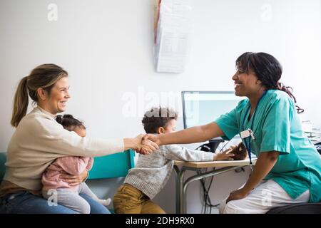 Lächelnde Ärztin und Frau, die in der Klinik die Hände schüttelt Stockfoto