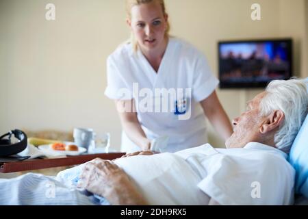 Krankenschwester, die dem älteren Mann auf der Krankenstation Frühstück serviert Stockfoto