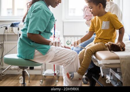 Mittelteil des Kinderarztes durch Jungen mit medizinischen Geräten in der Klinik Stockfoto