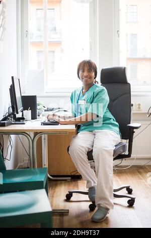 Portrait von reifen weiblichen Arzt arbeiten über Computer während des Sitzens In der Klinik Stockfoto