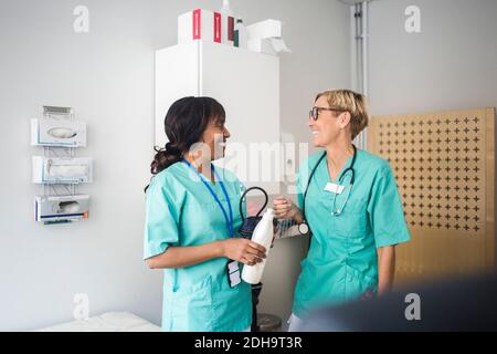 Lächelnde Kinderärztin, die im Stehen in der Klinik spricht Stockfoto