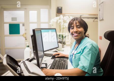 Portrait von reifen weiblichen Arzt mit Pony arbeiten über Computer Während der Sitzung in der Klinik Stockfoto