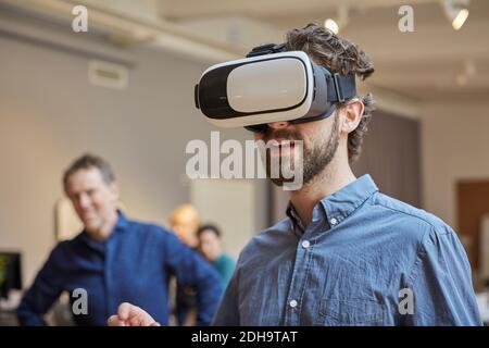 Männlich Profi mit Virtual-Reality-Simulator gegen Kollegen bei Creative Büro Stockfoto