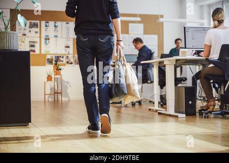 Unterer Abschnitt der leitenden weiblichen professionellen zu Fuß durch Kollegen in Kreatives Büro Stockfoto