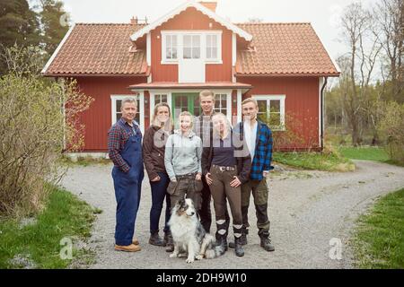 Porträt einer lächelnden Familie mit Australian Shepherd in voller Länge Auf Fußweg Stockfoto