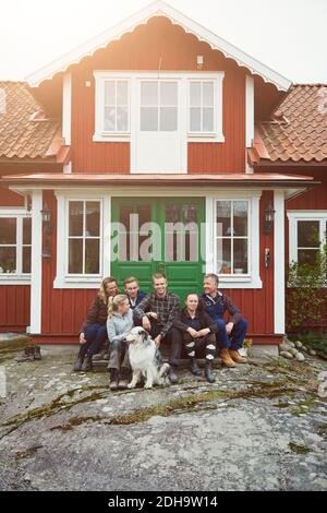 Lächelnde Familie, die mit Haustier am Eingang des Hauses sitzt Stockfoto