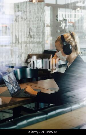 Geschäftsfrau mit Gesichtsmaske mit Videoanruf Stockfoto