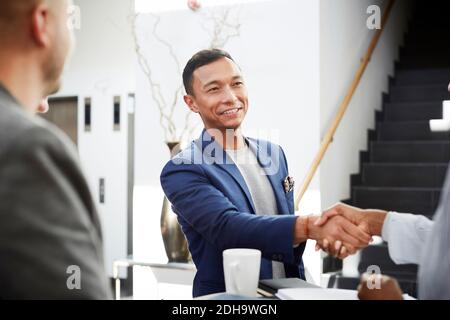 Lächelnder Unternehmer schüttelt die Hände mit Geschäftsfrau im Büro Stockfoto