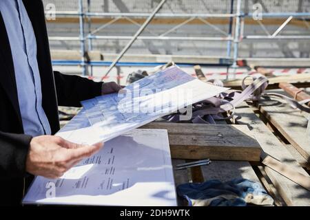 Mittelteil des Architekten mit Bauplan auf dem Tisch auf der Baustelle Stockfoto