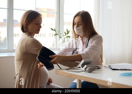 Arzt messen Blutdruck von ihrer schwangeren Patientin Stockfoto