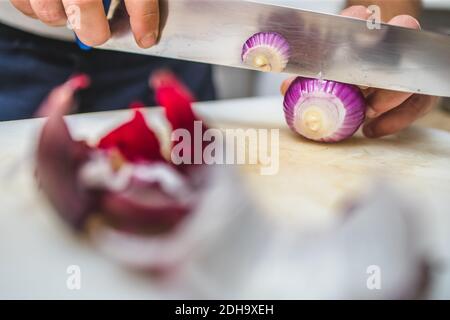 Koch schneidet rote Zwiebel auf dem Küchenbrett. Speisezubereitung im Restaurant Stockfoto