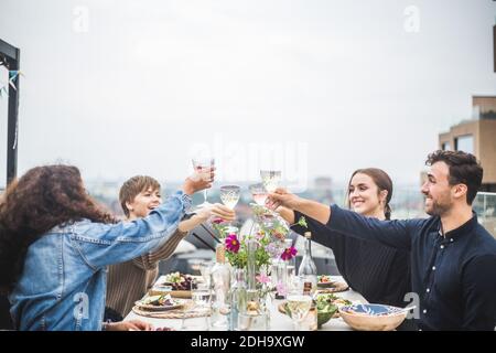 Männliche und weibliche Freunde, die beim Abendessen Wein toasten Während der Party auf der Terrasse Stockfoto