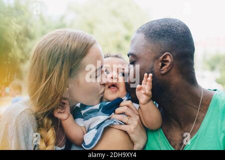 Nahaufnahme von multiethnischen Eltern küssen Sohn Stockfoto