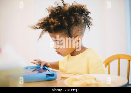 Nahaufnahme eines Jungen mit einem digitalen Tablet, während er am Tisch sitzt Stockfoto