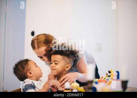 Glückliche Mutter umarmt Söhne zu Hause Stockfoto