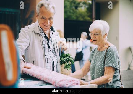 Ältere Paare, die auf dem Straßenmarkt in der Stadt Textilien kaufen Stockfoto