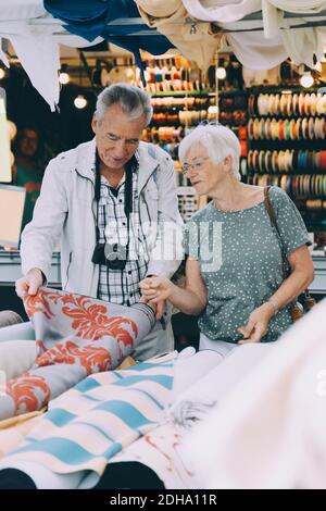 Älterer Mann zeigt der Frau beim Einkaufen Muster auf Stoff Auf dem Markt in der Stadt Stockfoto