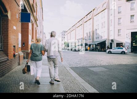 Rückansicht eines älteren Paares, das auf dem Bürgersteig in der Stadt läuft Während der Ferien Stockfoto