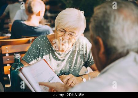 Ein älteres Touristenpaar diskutiert über die Speisekarte, während man im Restaurant sitzt Stadt Stockfoto