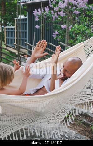 Vater und Sohn spielen, während sie in der Hängematte ruhen Stockfoto
