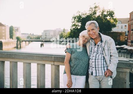 Porträt eines lächelnden älteren Paares, das Arm um das Geländer herum steht In der Stadt Stockfoto