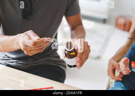 Vater, der dem Sohn Medizin gibt, der mit der Mutter zu Hause sitzt Stockfoto