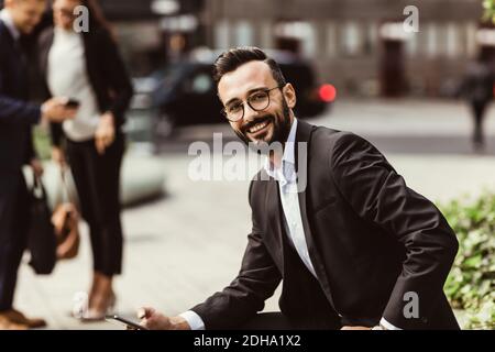 Porträt eines lächelnden Geschäftsmannes mit Mobiltelefon im Freien Stockfoto