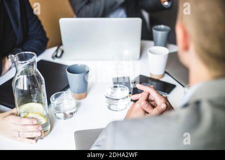 Mittelteil von Geschäftskollegen, die während des Büros im Vorstandszimmer sitzen Besprechung Stockfoto