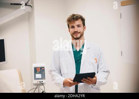 Porträt des selbstbewussten männlichen Arzt mit digitalen Tablet auf Krankenhaus Stockfoto
