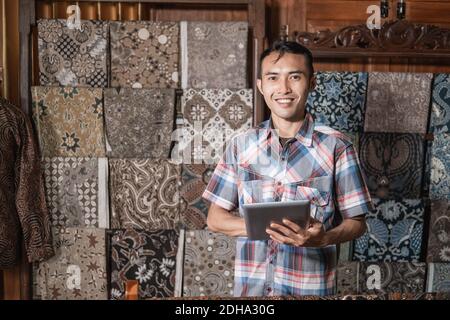 Portrait des jungen Kundenservice in traditionellem indonesischen Batik-Laden Stockfoto