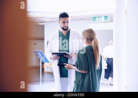 Junge männliche Arzt diskutieren mit weiblichen Krankenschwester in Krankenhaus-Lobby Stockfoto