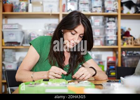 Reife weibliche Ingenieurin, die am Tisch in der Werkstatt arbeitet Stockfoto