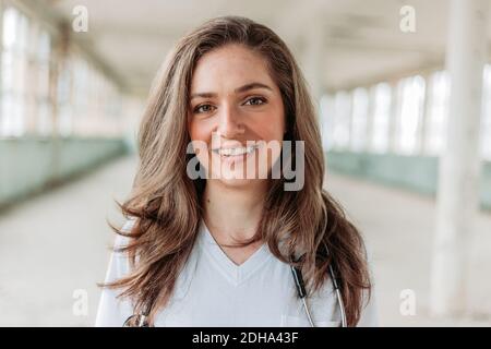 Junge blonde Ärztin lächelt. Unscharfer Hintergrund. Corona-Virus-Kampf Stockfoto