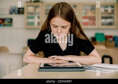 Studentin, die im Klassenzimmer auf ein digitales Tablet schaut Stockfoto