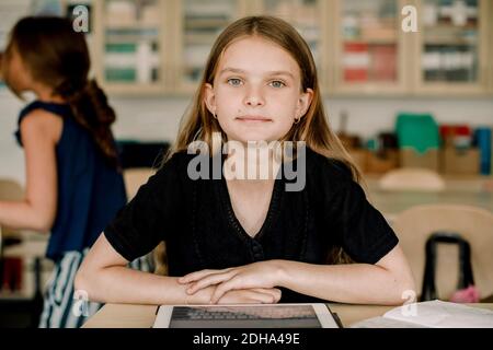 Portrait einer Studentin mit digitalem Tablet im Klassenzimmer