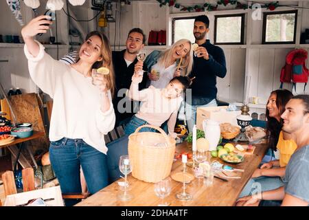 Junge Frau nimmt Selfie mit Freunden während der Mittagsparty Stockfoto