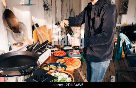 Mittelteil des jungen Mannes hält Olivenöl Flasche in der Küche Stockfoto