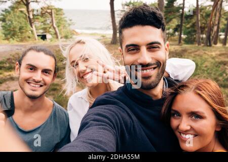 Glückliche männliche und weibliche Freunde, die Selfie im Wald machen Stockfoto