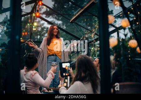 Junge Frau, die in der Glashütte für Freunde singt Stockfoto