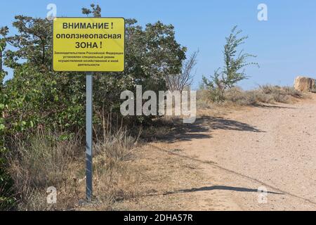 Schild mit der Aufschrift Achtung! Erdrutschgefahr! An der steilen Küste des Schwarzen Meeres auf der Nordseite der Stadt Sewastopol, Krim Stockfoto