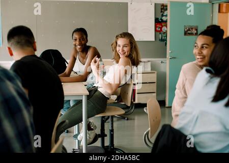 Lächelnde Schülerinnen sitzen im Klassenzimmer Stockfoto