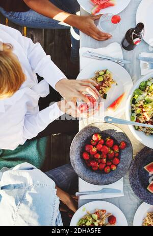 Blick auf multiethnische Freunde, die am Tisch zu Mittag essen An sonnigen Tag Stockfoto