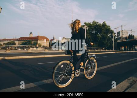 Seltene Ansicht der weiblichen Exekutive Fahrrad fahren auf der Straße in Stadt gegen Himmel Stockfoto