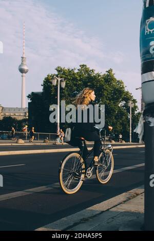 Volle Länge der weiblichen Exekutive Fahrrad auf der Straße in Stadt gegen Himmel Stockfoto